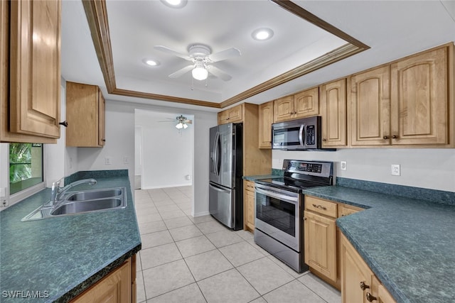 kitchen featuring a tray ceiling, ornamental molding, sink, light tile patterned floors, and appliances with stainless steel finishes