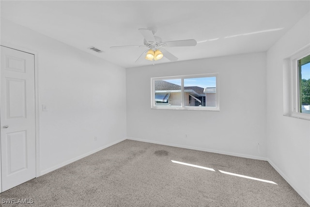 carpeted spare room featuring ceiling fan and a wealth of natural light