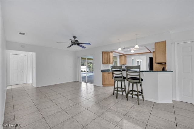 kitchen with kitchen peninsula, light tile patterned floors, hanging light fixtures, and ceiling fan