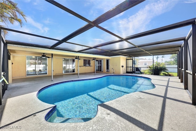 view of swimming pool with ceiling fan, glass enclosure, and a patio area