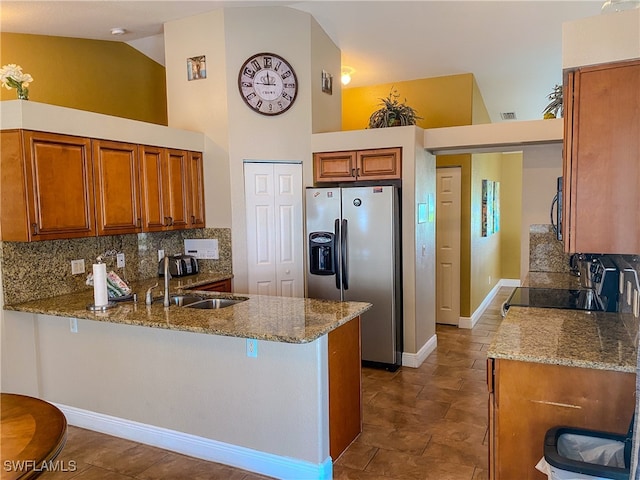 kitchen with kitchen peninsula, tasteful backsplash, stainless steel fridge with ice dispenser, black range, and light stone counters