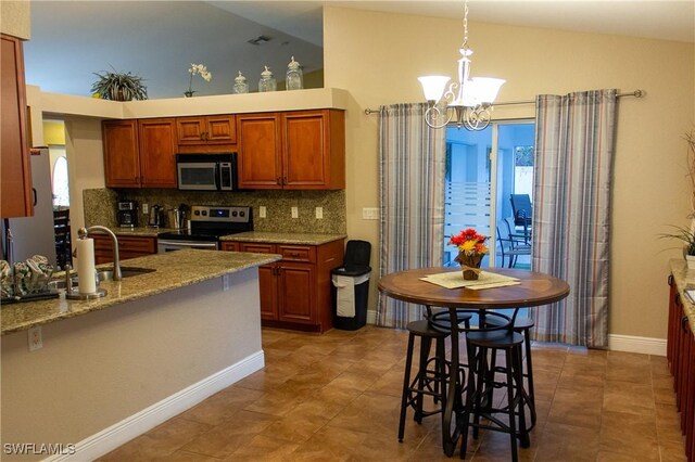 kitchen with light stone countertops, hanging light fixtures, stainless steel appliances, lofted ceiling, and decorative backsplash