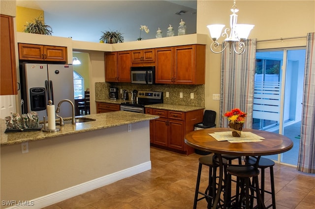 kitchen with decorative backsplash, light stone countertops, stainless steel appliances, sink, and decorative light fixtures