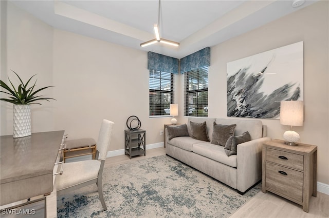 living room with a tray ceiling and light wood-type flooring