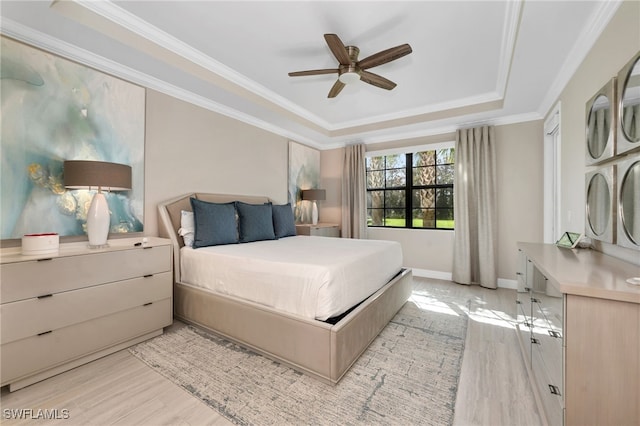 bedroom featuring ceiling fan, a tray ceiling, light hardwood / wood-style flooring, and crown molding