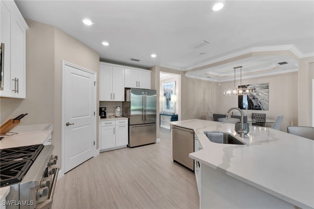 kitchen featuring appliances with stainless steel finishes, white cabinets, sink, and hanging light fixtures