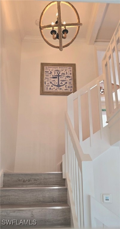 stairway featuring an inviting chandelier, crown molding, and a towering ceiling