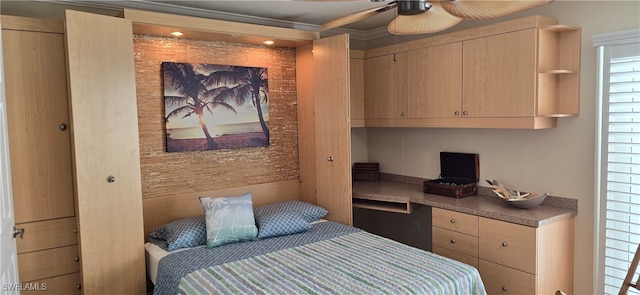 bedroom with ornamental molding, built in desk, and ceiling fan