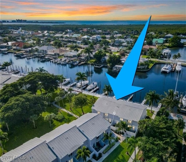 aerial view at dusk featuring a water view