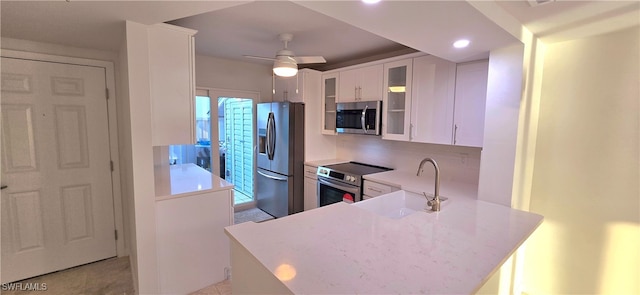 kitchen featuring kitchen peninsula, ceiling fan, backsplash, white cabinetry, and appliances with stainless steel finishes