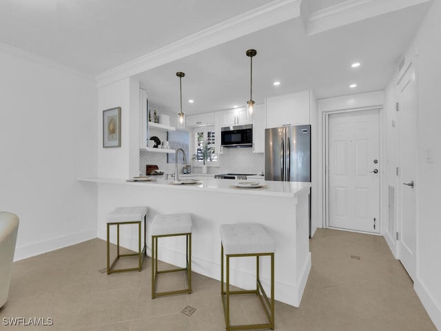 kitchen featuring backsplash, kitchen peninsula, stainless steel appliances, decorative light fixtures, and white cabinets