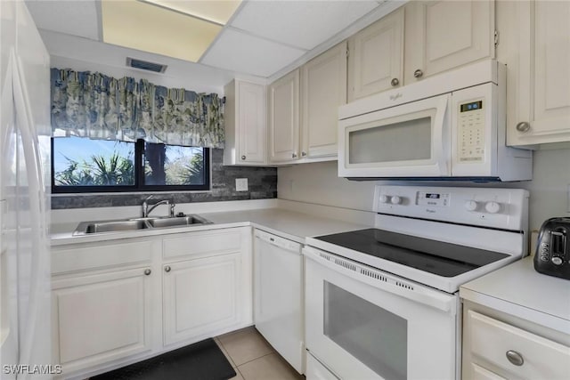 kitchen featuring a drop ceiling, white appliances, a sink, visible vents, and light countertops