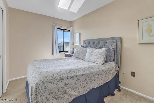 bedroom featuring lofted ceiling with skylight and light colored carpet