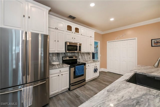 kitchen featuring decorative backsplash, appliances with stainless steel finishes, white cabinetry, and light stone counters