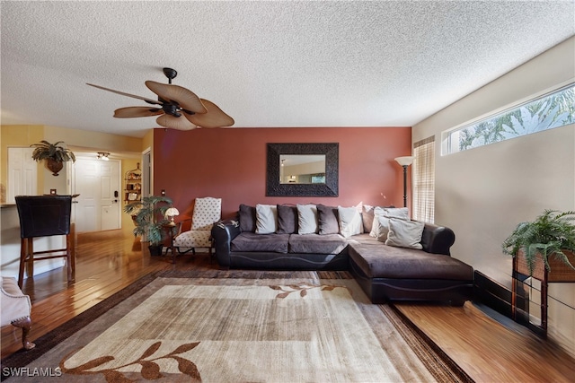 living room featuring a textured ceiling, wood-type flooring, and ceiling fan