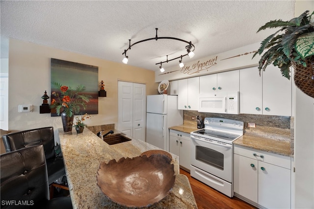 kitchen with kitchen peninsula, white cabinets, sink, and white appliances