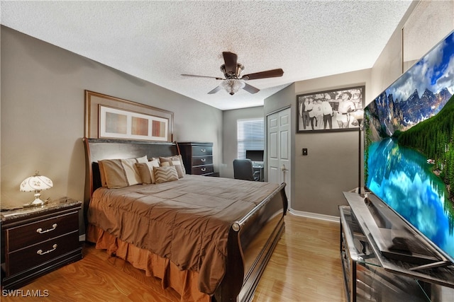 bedroom with a closet, ceiling fan, a textured ceiling, and light hardwood / wood-style flooring