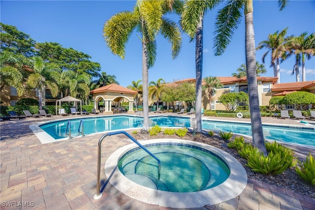 view of swimming pool featuring a patio and a hot tub