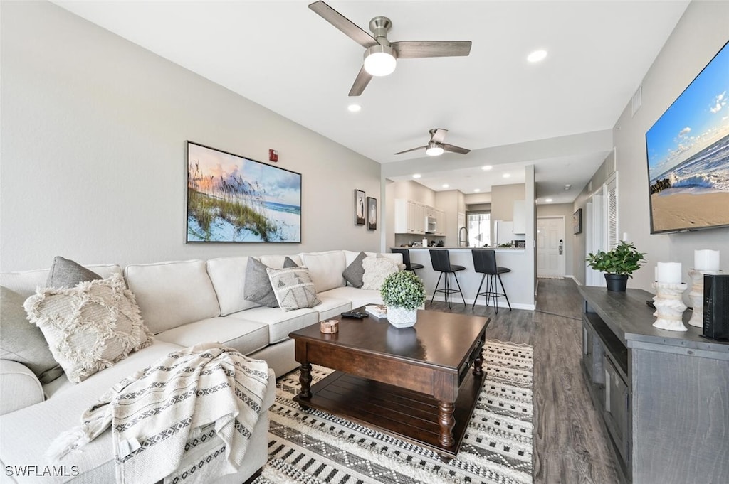 living room with hardwood / wood-style flooring, ceiling fan, and sink