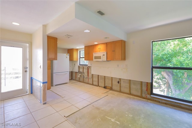 kitchen featuring white appliances, light tile patterned floors, and plenty of natural light