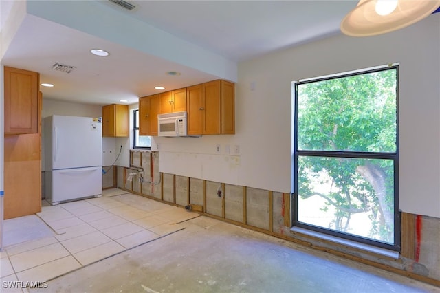 kitchen featuring white appliances, a healthy amount of sunlight, and light tile patterned floors