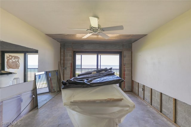 interior space with a water view and ceiling fan