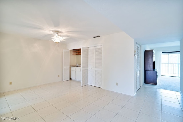 tiled empty room featuring ceiling fan