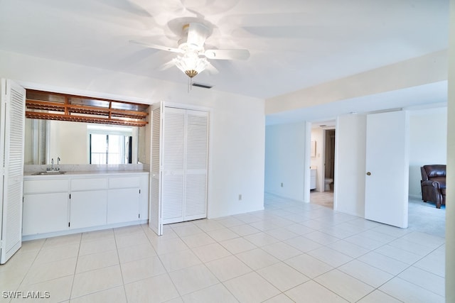 empty room with ceiling fan, sink, and light tile patterned floors