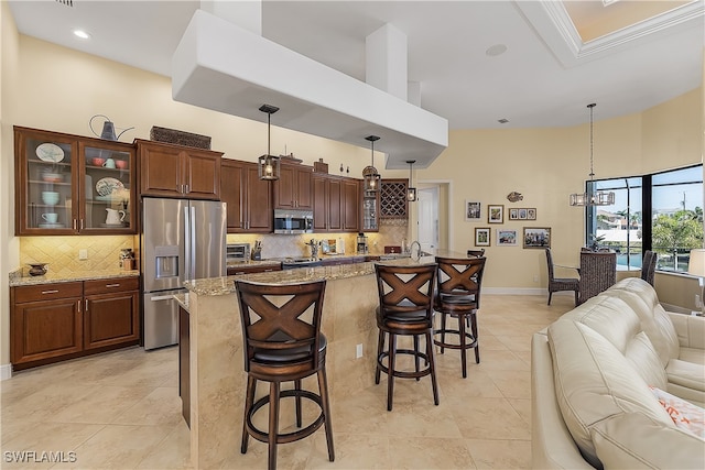 kitchen with a large island, light stone countertops, stainless steel appliances, and pendant lighting