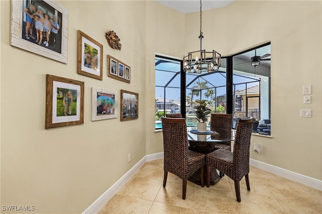 dining space with a towering ceiling, light tile patterned floors, and ceiling fan with notable chandelier