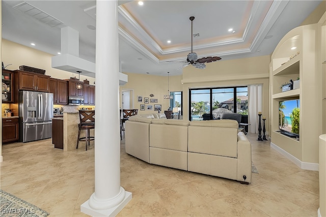 living room featuring decorative columns, a raised ceiling, crown molding, and ceiling fan