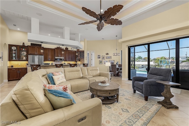 tiled living room featuring a towering ceiling, crown molding, a raised ceiling, and ceiling fan