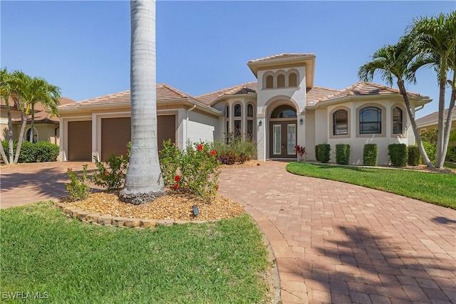 mediterranean / spanish house featuring french doors, a front yard, and a garage