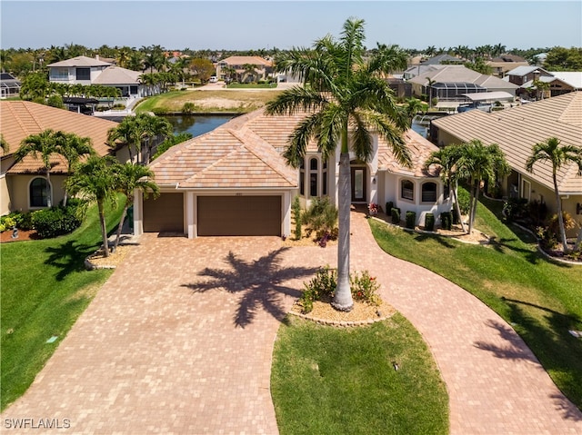 mediterranean / spanish house featuring a front lawn, a garage, and a water view