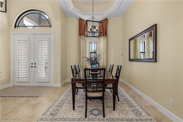 dining area with an inviting chandelier, ornamental molding, plenty of natural light, and a raised ceiling