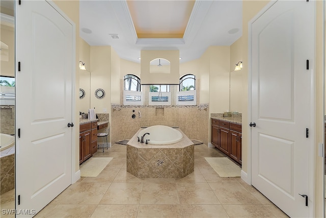 bathroom featuring vanity, tiled tub, a raised ceiling, and tile patterned floors