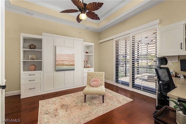 home office featuring ornamental molding, dark wood-type flooring, a raised ceiling, and ceiling fan