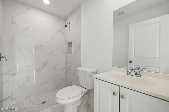 bathroom featuring tiled shower, vanity, and toilet