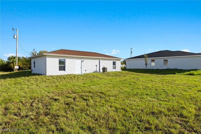 rear view of property featuring a lawn and cooling unit