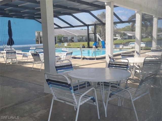 view of patio with glass enclosure and a community pool