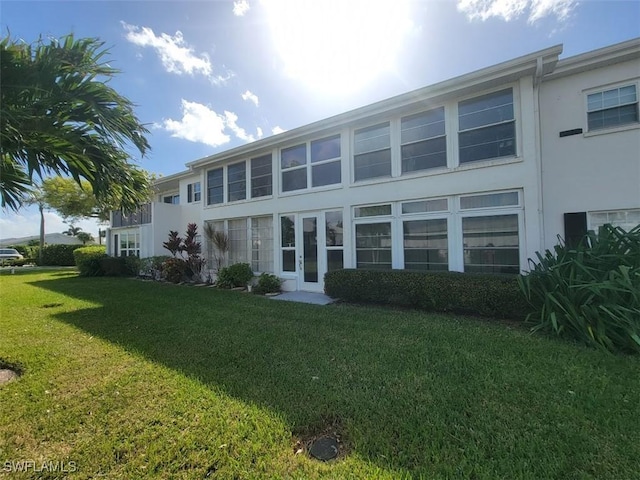 rear view of house with a lawn and stucco siding