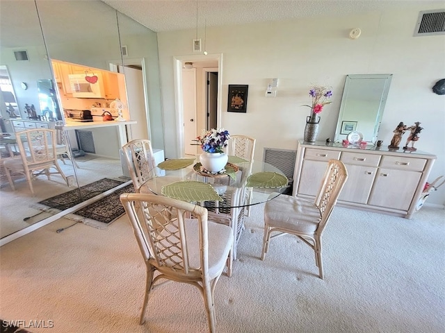 dining space featuring a textured ceiling and light colored carpet