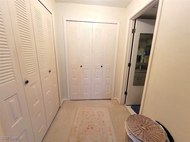 corridor with light carpet and a textured ceiling