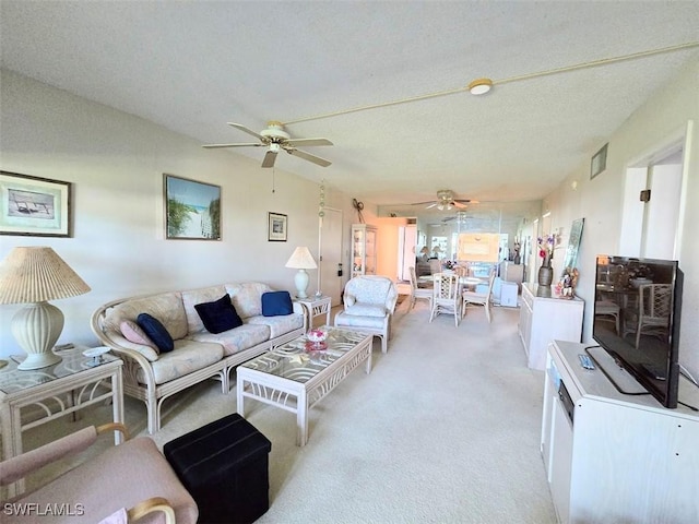 living room featuring light carpet, ceiling fan, visible vents, and a textured ceiling