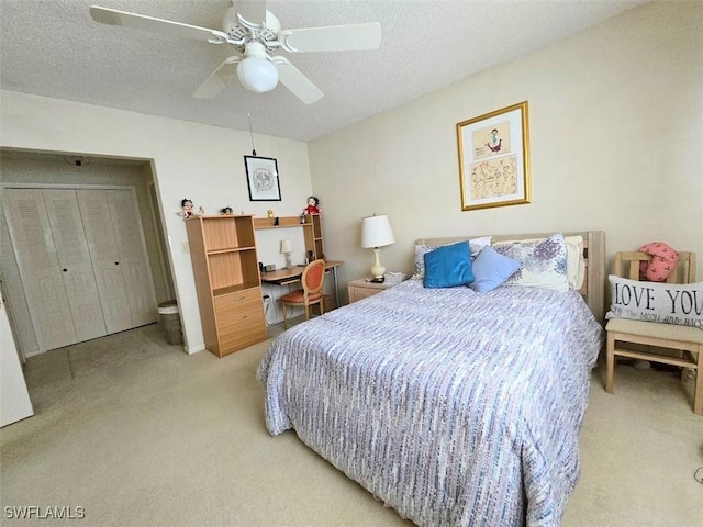 bedroom featuring a ceiling fan, light colored carpet, and a textured ceiling