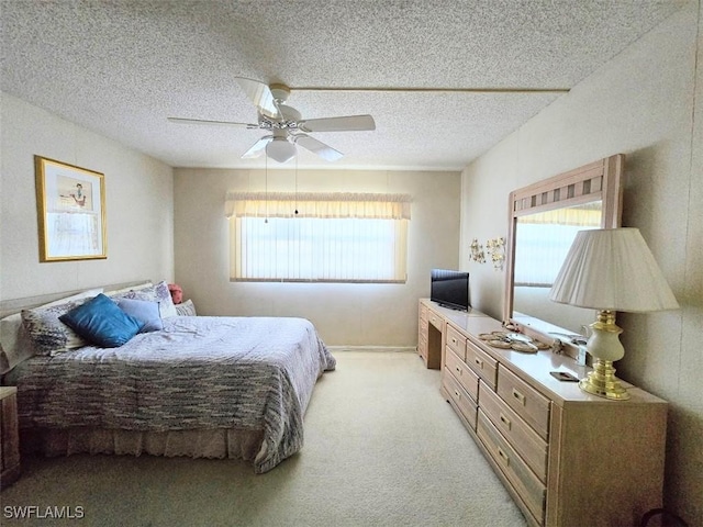 bedroom featuring light carpet, ceiling fan, and a textured ceiling