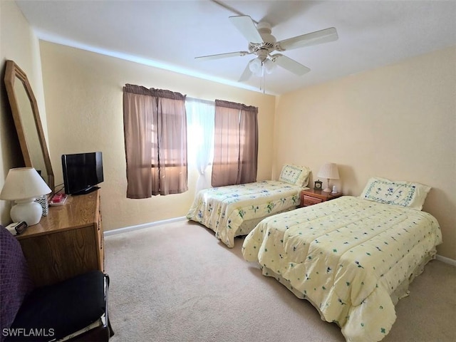 bedroom with a ceiling fan, light carpet, and baseboards