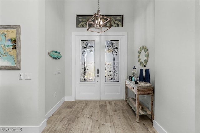 entrance foyer featuring an inviting chandelier, french doors, and light wood-type flooring