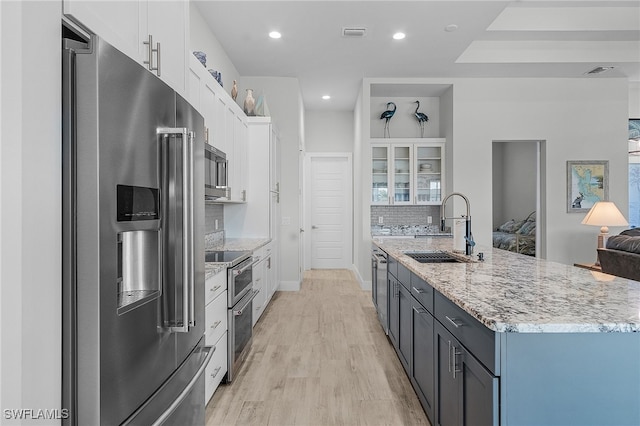 kitchen featuring decorative backsplash, white cabinets, light hardwood / wood-style flooring, sink, and stainless steel appliances