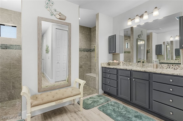 bathroom with vanity, a tile shower, and wood-type flooring